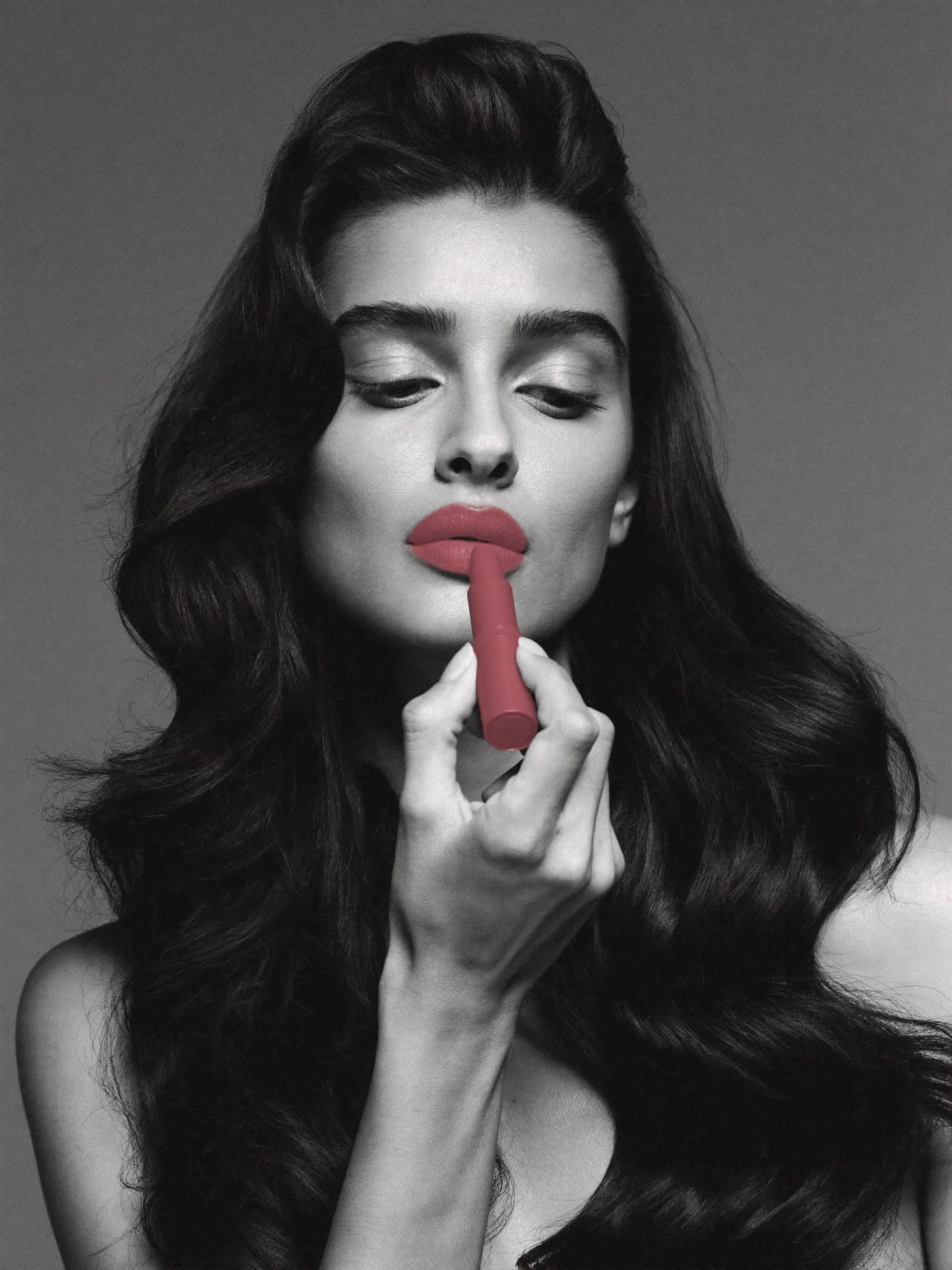 Retrato en blanco y negro de una mujer aplicándose un labial mate en teddy tint